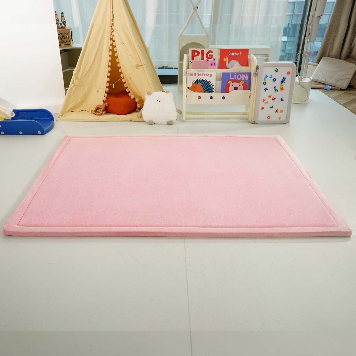 Реална снимка на розов детски мемори килим GINGER HOME LOLLA, поставен в детска стая с играчки и мебели. 